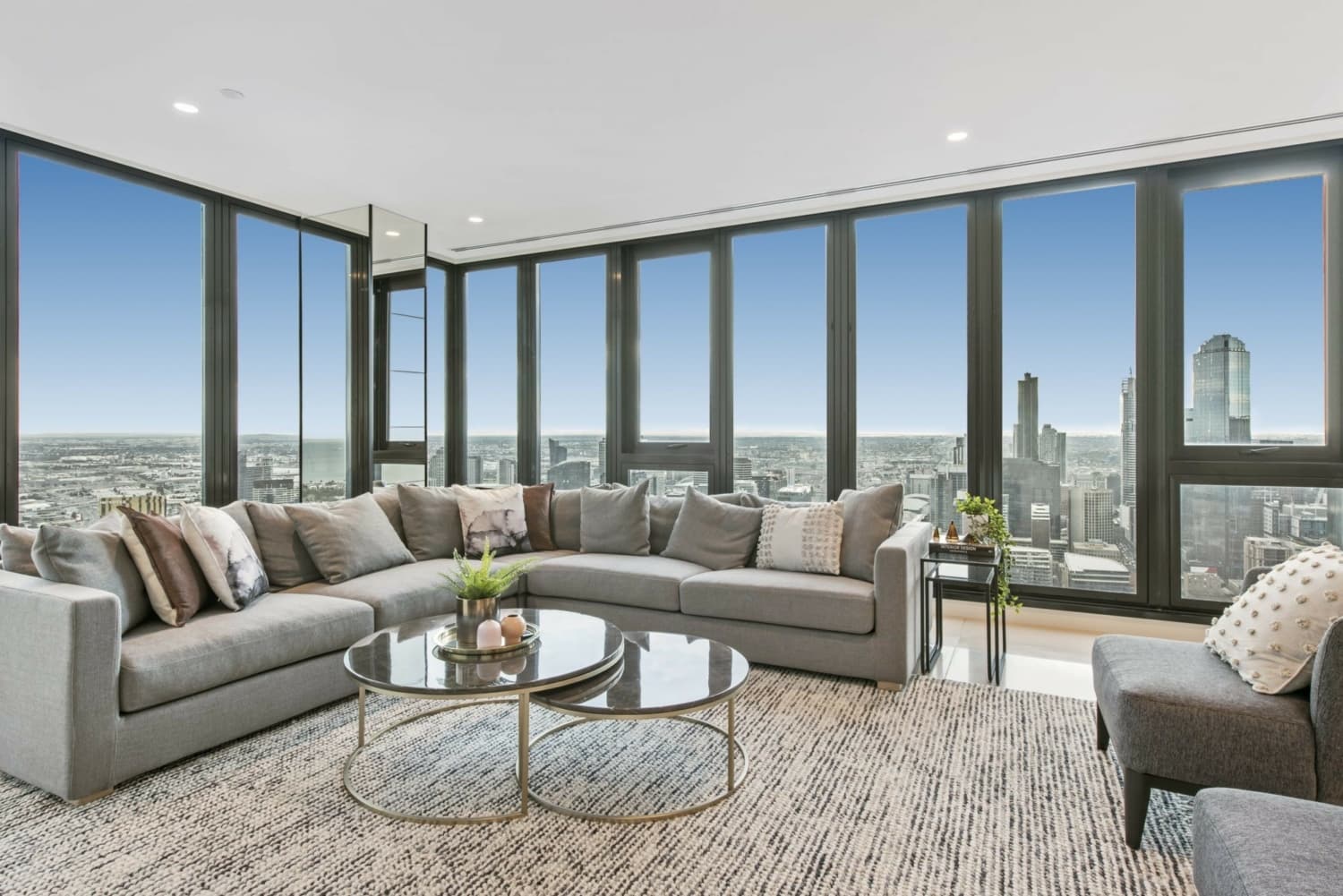 Melbourne King's Birthday Weekend: Modern apartment with city view. Gray sofa, coffee tables, and large windows.